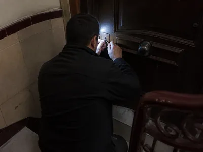 Escalera de noche en Barcelona con luz de trabajo junto a una puerta de madera.